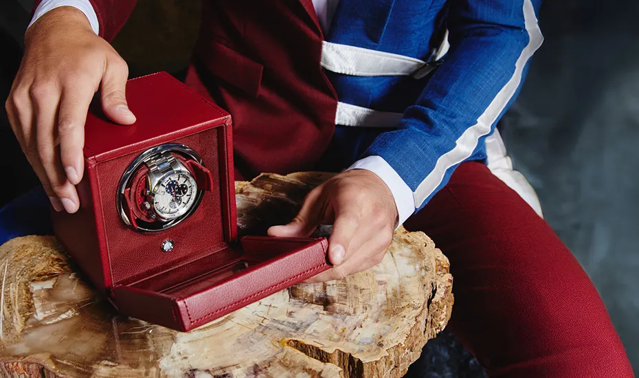 Man placing watch in red WOLF winder box