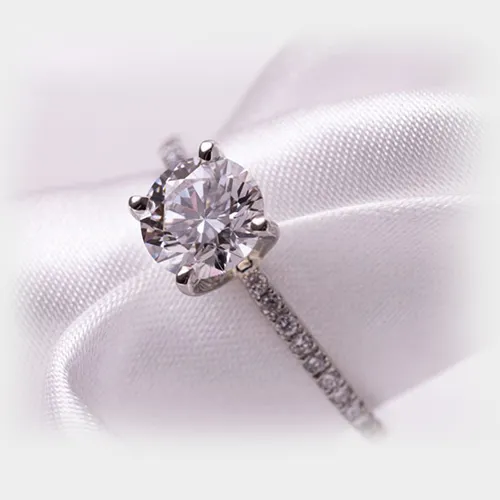 Solitaire diamond ring on white satin ribbon in close-up shot